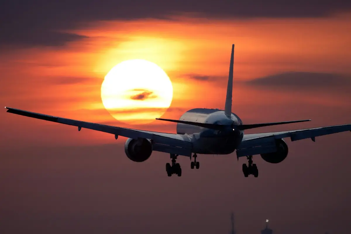 Avião em aproximação para pouso contra o pôr do sol