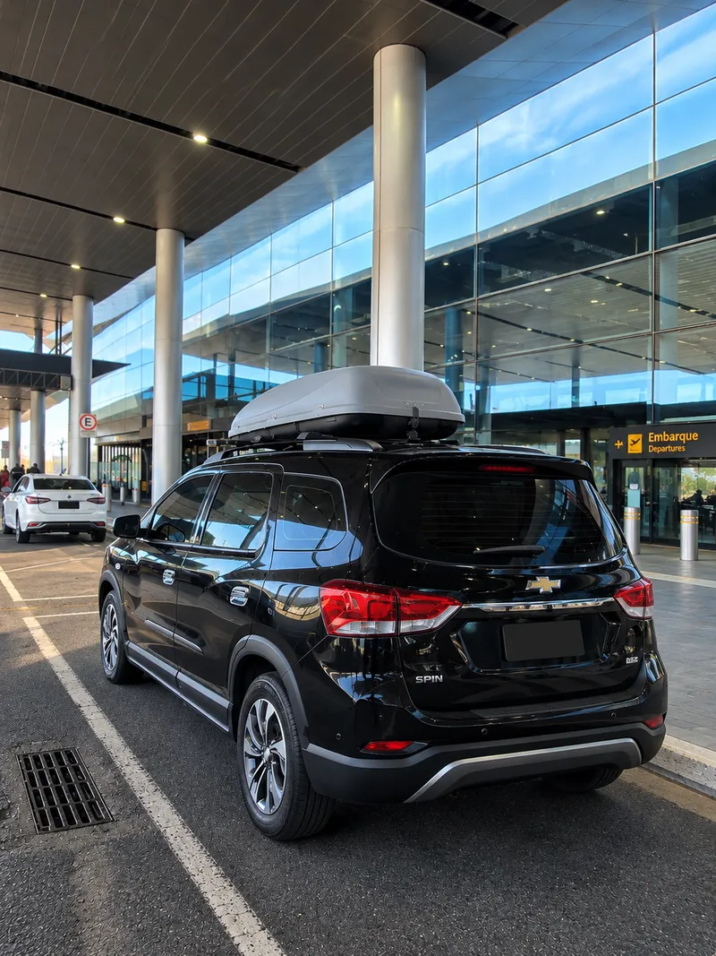Chevrolet Spin preta com bagageiro no teto, na área de embarque de um aeroporto